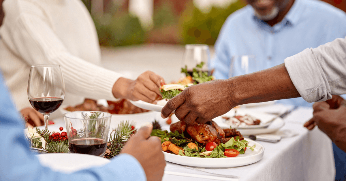 People sharing a meal with wine at a farm-style table 